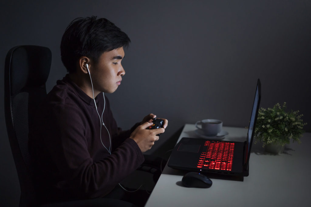 man playing with controller on gaming laptop