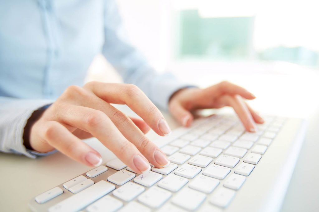 woman typing on white laptop keyboard