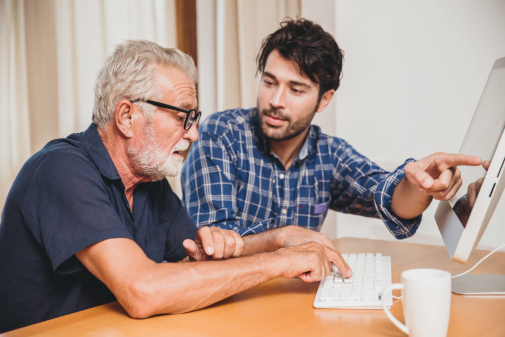 son showing his grandfather how to use a computer